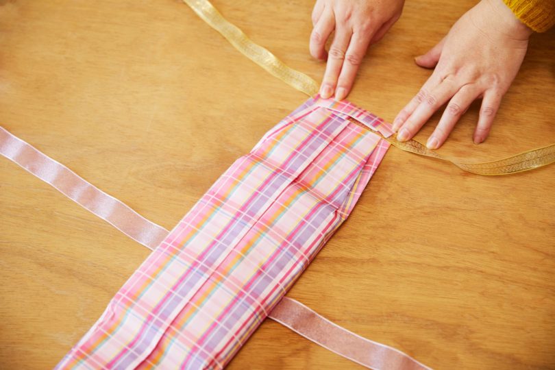 内側に折った上下を開き、タオル中央の下にリボン1本を敷く。
