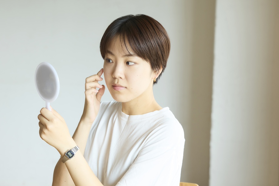 鏡を見ながら肌の状態を確認する女性